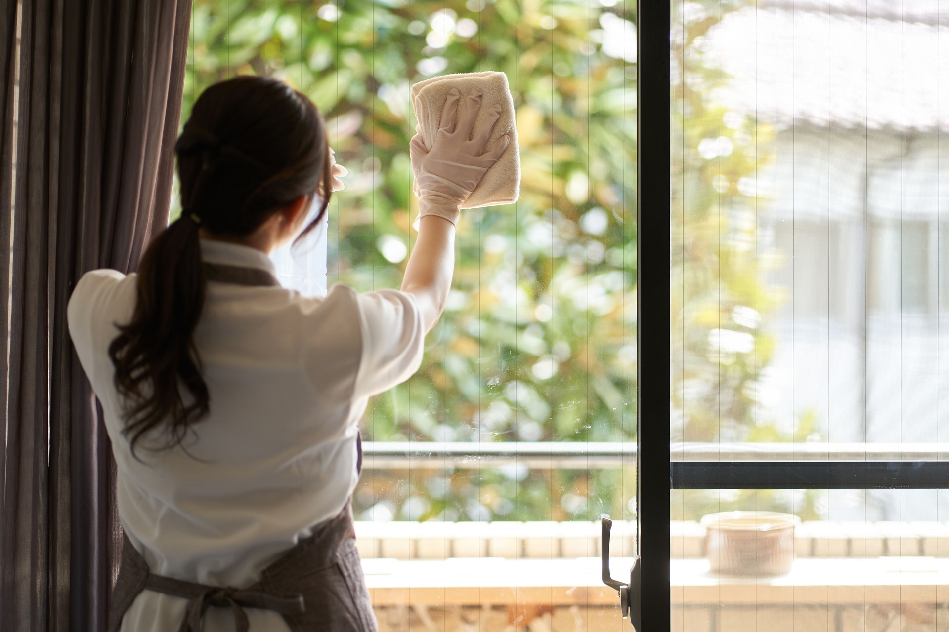 Asian woman cleaning the living room window